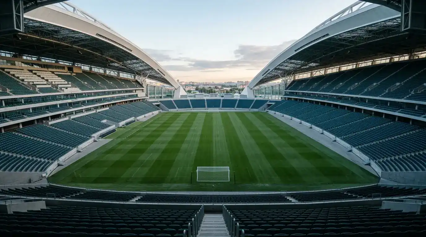 Tomt fodboldstadion i morgenlys efter en afsluttet turnering, med velplejet grønt græs